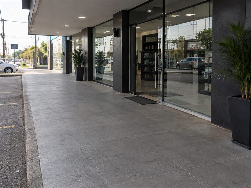 Calçada de galeria comercial com piso de granito cinza limpo em frente às vitrines das lojas