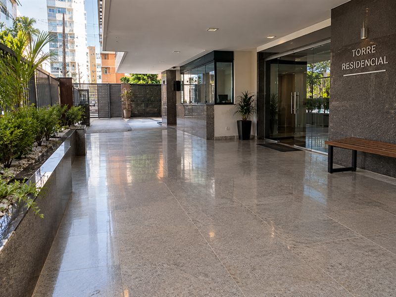 Entrada de condomínio residencial com piso de granito claro e brilhante