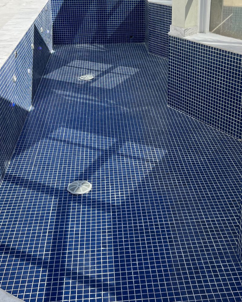 Piscina de pastilhas azuis com rejunte branco e uniforme depois do rejuntamento