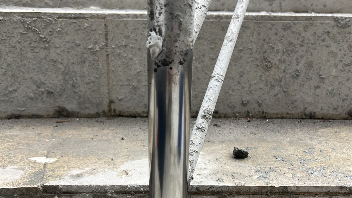 Coluna de corrimão em inox com a parte de baixo já polida e a de cima ainda suja de obra