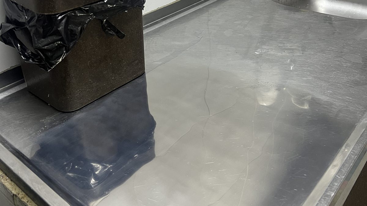Bancada de cozinha em inox polida, refletindo os objetos
